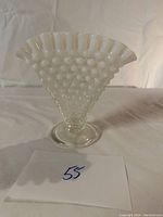 Front view showing white hobnail milk glass vase with ruffled edge and round base.