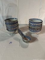 The full set of 13 vintage blue and white Chinese rice bowls and 5 matching spoons arranged in two stacks and a group.