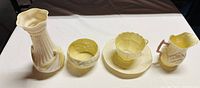 Display of four Belleek ceramic items including vase, bowl, cup and saucer, and creamer jug.