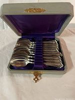 Ten spoons arranged in original hinged box with purple satin and velvet slots