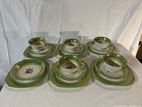 Wide shot showing 5 complete sets of teacup, saucer, and plate, one teacup missing from the full set