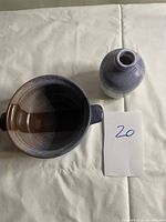 Photo showing the pair of pottery pieces on white fabric background with a card showing number 20. The bowl shows interior and exterior glazing, the vase is positioned next to it.