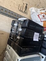 Four Xbox 360 consoles stacked, one white and three black units, shown with visible surface wear and tape on one black unit.