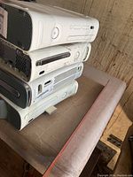 Four stacked white Xbox 360 consoles of different versions and conditions, untested.