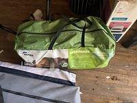Green Napier Backroadz SUV Tent bag with clear branding and model number 191, shown on wooden floor with some household items around.