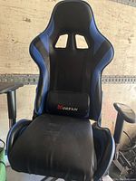 Front-facing view of Morfan gaming chair showing black and blue fabric, lumbar pillow, and adjustable armrests.