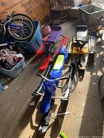 Photo showing three GT snowracers positioned in a row on a wooden floor alongside bikes and other items.