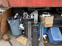 Two large garbage cans and one box filled with ice skates, next to a GT Snow Racer sled