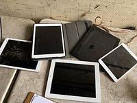 Photo of five iPads, some with cracked screens and all untested.