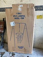 Closed cardboard box containing a Jolly Jumper Model #108 baby jumper swing with graphic illustration on the box.