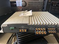 Side view focusing on speaker output terminals, battery and ground connections, and fuse holder on the amplifier.