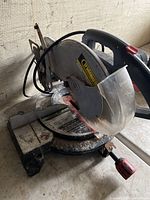 Trademaster mitre saw resting at an angle, showing the rusted cutting disc and adjustable base