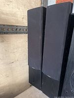 Pair of Paradigm tower speakers shown upright with black fabric grills and black wood veneer cabinets.