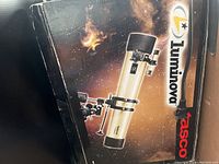 Photo of the Tasco Luminova telescope in its original box with space background graphics and visible brand logos.