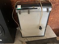 Photo showing vintage General Electric x-ray illuminator with illuminated surface, metal clips, power cord attached.