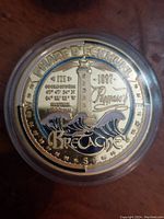 Close-up of Bretagne Phare d'Eckmühl 1897 coin showing lighthouse, coordinates, waves, and lettering
