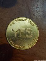 Photo of coin front side showing 'YES', 'THE BRONZE SHOP' and 'VANCOUVER CANADA' engravings.
