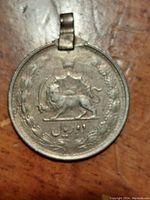 Front side of the vintage Iranian coin pendant featuring a crowned lion holding a sword, surrounded by a laurel wreath with Persian inscriptions.