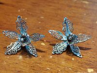 Front view of a pair of vintage sterling silver stud filigree orchid earrings showing delicate openwork petals and leaves.