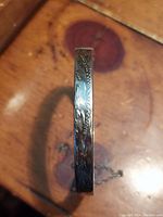 Close-up photo showing the floral etched pattern on the outer surface of the silver bangle.