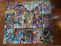 Photo showing all 15 vintage 1990s DC Comics superhero comic books laid out on floor, including Superman, Superwoman, and Supergirl covers.