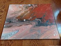Flat lay photo showing the vintage original abstract 'Agate' oil painting on stretched canvas with agate-like swirling patterns in red, gray, black, and white colors.