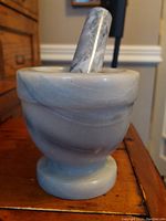 Side view of the circular stone mortar and part of the pestle resting inside.