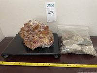 Full lot showing the large calcite crystal specimen on black plinth with bag of additional minerals to the right.