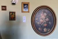 Wide view showing all four framed floral art pieces hung on wall, including large oval and three smaller rectangular and square pieces
