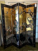 Front view of four-panel folding screen showing cranes and floral motifs on gold background