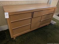 Front view of vintage wooden dresser showing nine drawers with horizontal pull fronts.