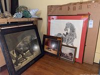 Overview of five visible framed prints leaning against wall with packing board