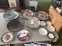 All plates and saucers arranged on table including cranes, waves, cherry blossom plates, and others
