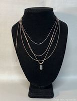 Front view of four 925 silver necklaces displayed on black stand showing different chain styles and pendant.