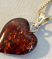 Close-up of heart-shaped amber pendant showing deep reddish-brown color and inclusions