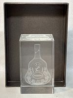 Crystal block showing laser-etched Hennessy XO bottle design inside, placed inside the box lid.
