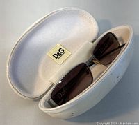 Top view of Dolce&Gabbana sunglasses inside original white zippered case with soft lining and D&G logo patch inside the case