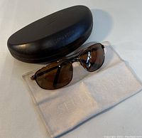 Serengeti sunglasses laid out in front of a black hard case and white cleaning cloth