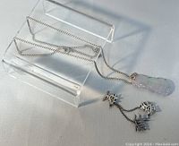 Clear image of silver chain necklace with light lavender-green carved jade pendant displayed on clear stand.