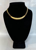 Front view of the vintage gold-tone choker necklace with crystal rhinestone encrusted curved pendant on display stand.