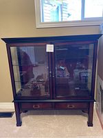 Full front view of the wooden china cabinet showing glass doors and wooden frame with two drawers below