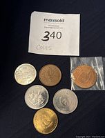 Six Canadian collector coins in various metals and designs, grouped on black fabric background with lot number tag.