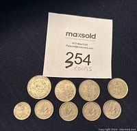 Photo showing all 10 coins arranged in a pyramid shape on a black fabric background with a MaxSold tag indicating 354 coins.