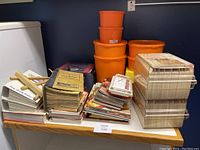 Full view of stacked cookbooks and vintage orange Tupperware containers on a small table.