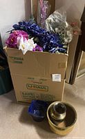 Box filled with assorted artificial flowers in multiple colors, with three plant pots placed in front of the box.