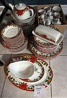 Full view of holiday dinnerware set showing stacked plates, mugs in box, teapot on top. Presents the quantity and design of set.