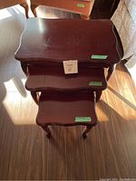 Top-down view of three stacked nesting tables showing curved edges and wood finish.