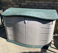 Front view of shed showing green curved lid and tan double doors