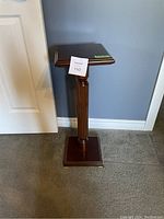 Front view of the wooden plant stand showing the square base and decorative central column.