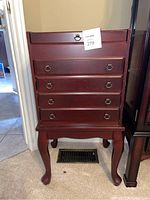 Wooden silverware chest, tall with four drawers and ring pull handles, dark reddish wood, standing on cabriole legs